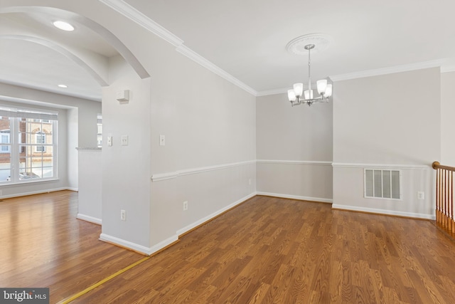 spare room with crown molding, hardwood / wood-style floors, and a notable chandelier