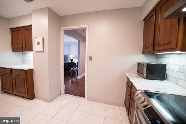 kitchen with light tile patterned flooring, tasteful backsplash, and electric stove