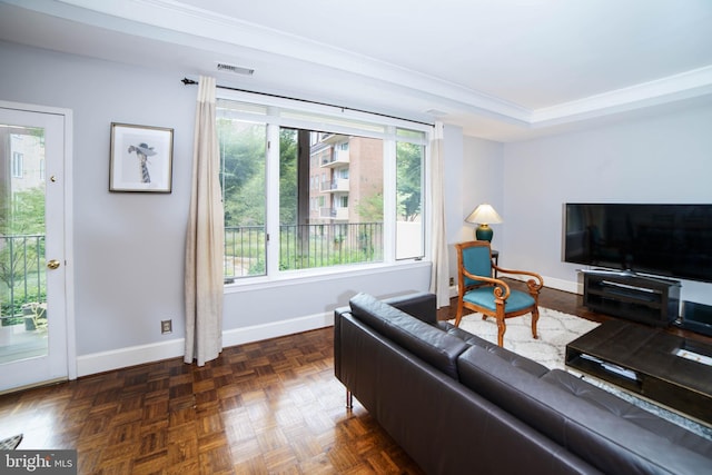 living room featuring dark parquet flooring, crown molding, and plenty of natural light