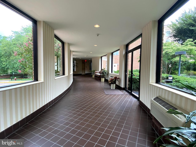 unfurnished sunroom featuring a wall unit AC and a wealth of natural light