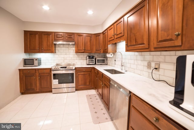 kitchen with tasteful backsplash, sink, light tile patterned flooring, and stainless steel appliances