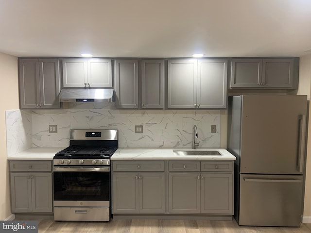 kitchen with tasteful backsplash, gray cabinets, sink, and appliances with stainless steel finishes