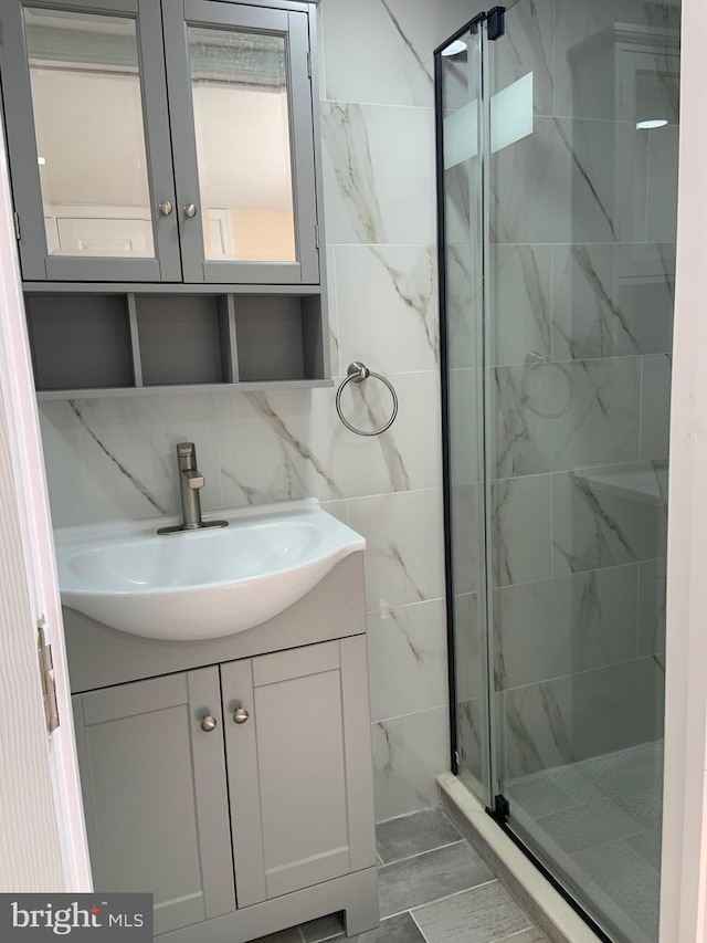 bathroom with backsplash, tile walls, vanity, and an enclosed shower