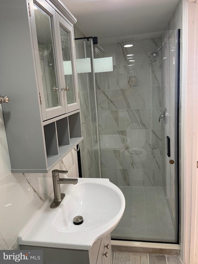 bathroom featuring vanity, decorative backsplash, and a shower with door