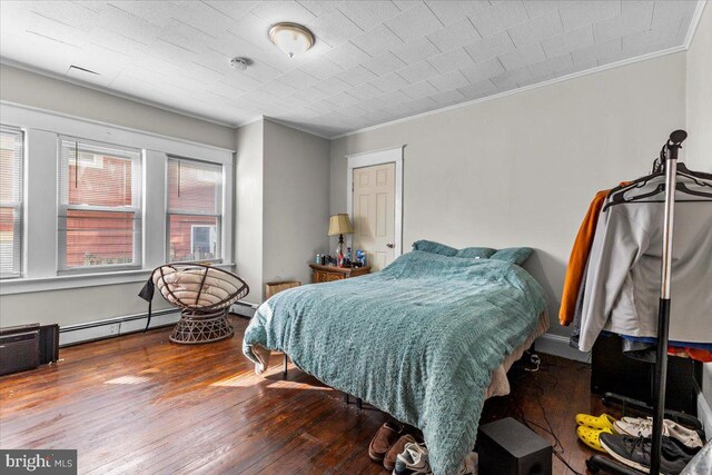 bedroom with hardwood / wood-style floors, crown molding, and a baseboard heating unit