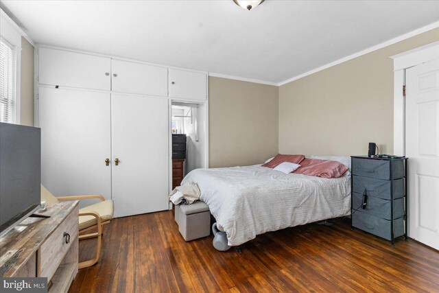 bedroom featuring dark hardwood / wood-style floors, ornamental molding, and a closet