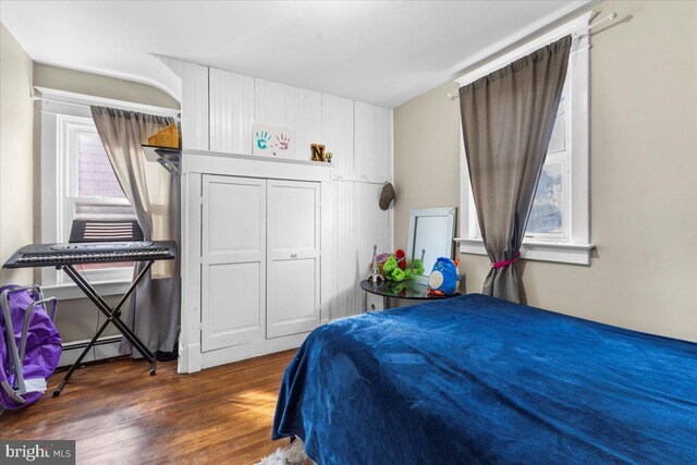 bedroom featuring dark hardwood / wood-style floors and a baseboard heating unit