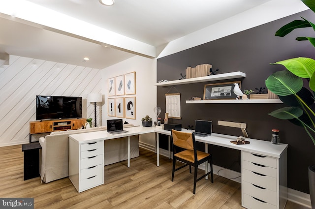 home office with wood walls, built in desk, and light hardwood / wood-style flooring