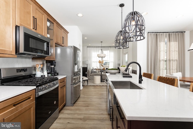 kitchen featuring a chandelier, a kitchen island with sink, pendant lighting, and stainless steel appliances