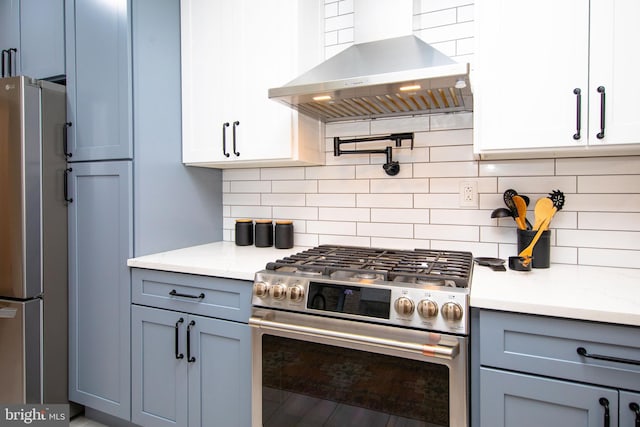 kitchen with tasteful backsplash, appliances with stainless steel finishes, wall chimney range hood, and light stone counters