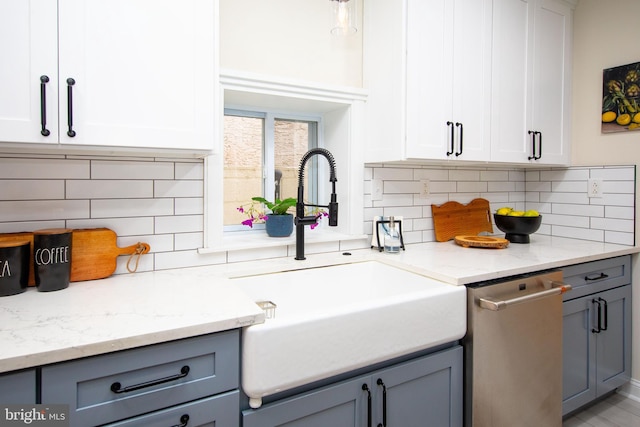 kitchen featuring tasteful backsplash, sink, stainless steel dishwasher, and white cabinets