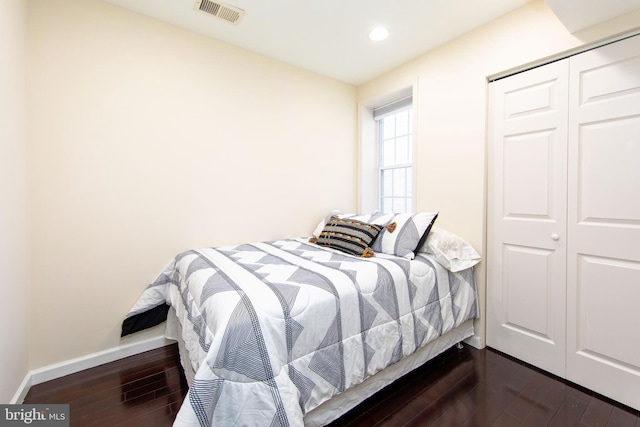 bedroom with dark hardwood / wood-style flooring and a closet