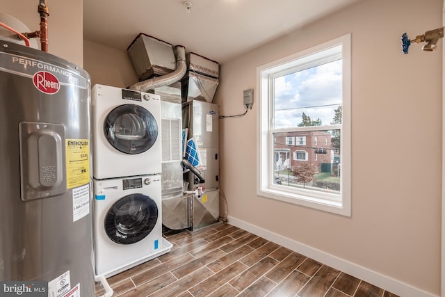 washroom featuring heating unit, electric water heater, and stacked washer / drying machine