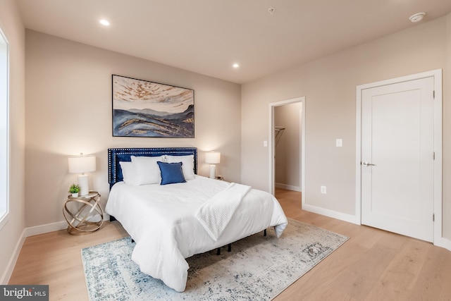 bedroom featuring a spacious closet, a closet, and light wood-type flooring