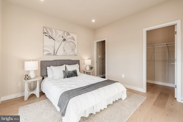 bedroom with a walk in closet, a closet, and light hardwood / wood-style floors