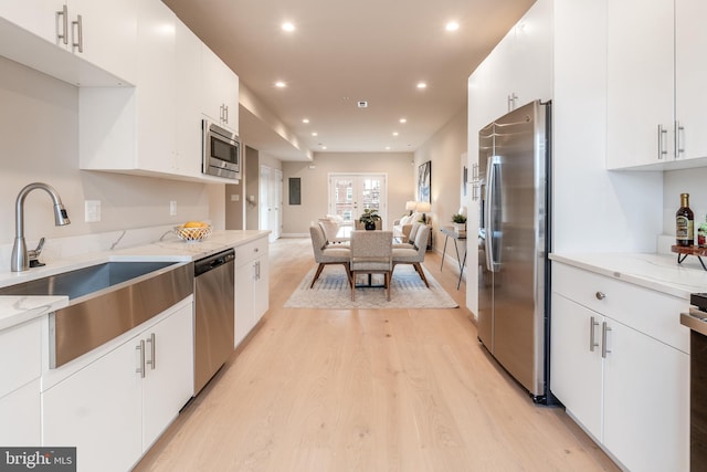 kitchen with white cabinetry, sink, light wood-type flooring, and appliances with stainless steel finishes