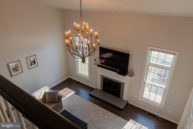 living room with dark wood-type flooring, plenty of natural light, and a chandelier