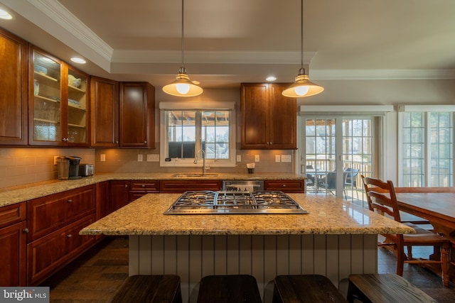 kitchen with sink, stainless steel appliances, light stone counters, a kitchen bar, and decorative light fixtures