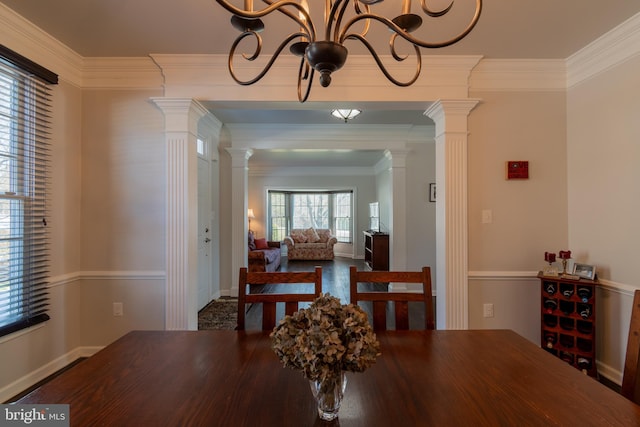 dining space featuring a notable chandelier, ornamental molding, and decorative columns