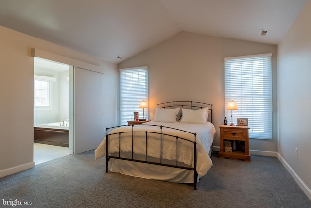 carpeted bedroom featuring lofted ceiling and ensuite bath