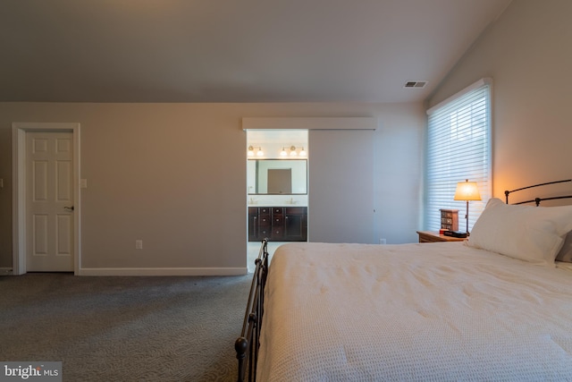 unfurnished bedroom with lofted ceiling, ensuite bathroom, and dark carpet