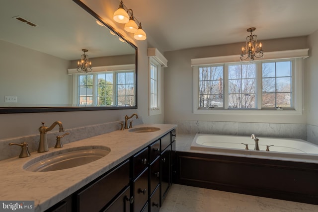 bathroom featuring vanity, a bathing tub, and an inviting chandelier