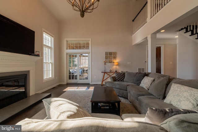 living room with a towering ceiling, dark hardwood / wood-style floors, and a chandelier