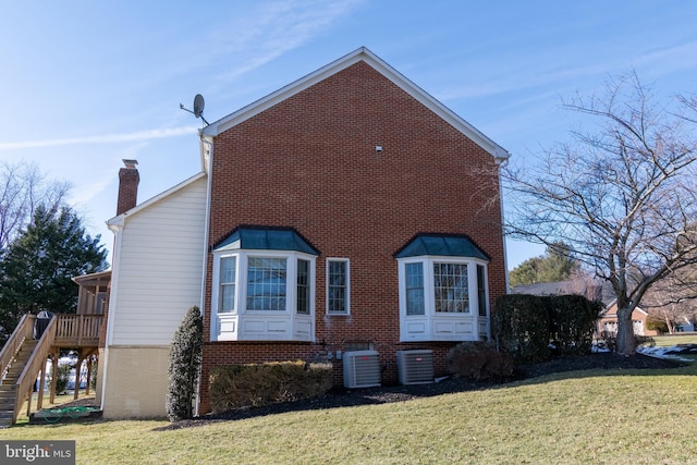 view of side of home featuring a lawn and central air condition unit