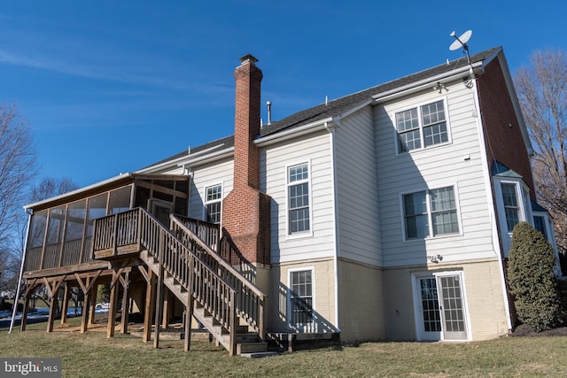 rear view of house featuring a yard, a deck, and a sunroom