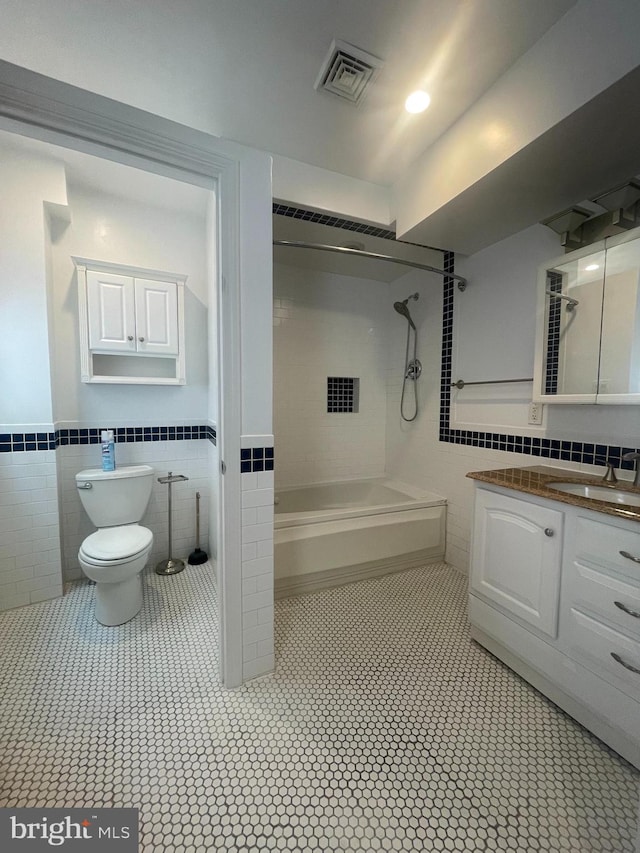 bathroom featuring toilet, vanity, tile patterned floors, and tile walls