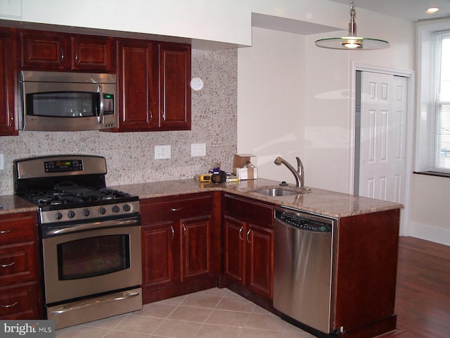 kitchen featuring light stone countertops, decorative backsplash, sink, and stainless steel appliances