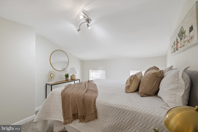 bedroom with carpet flooring, vaulted ceiling, and rail lighting