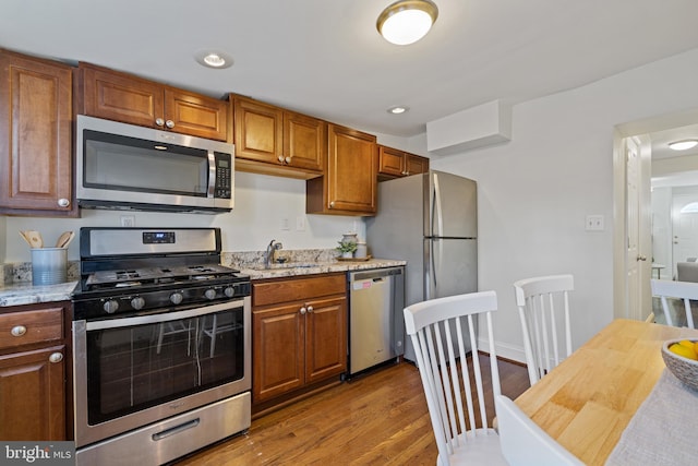 kitchen with light stone counters, sink, dark wood-type flooring, and appliances with stainless steel finishes