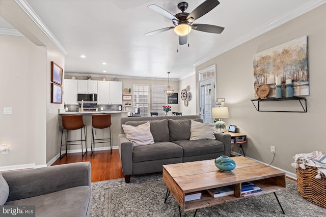 living room with ceiling fan, ornamental molding, and dark wood-type flooring