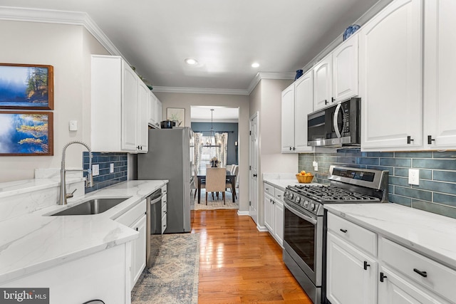 kitchen with white cabinets, sink, appliances with stainless steel finishes, and light hardwood / wood-style flooring