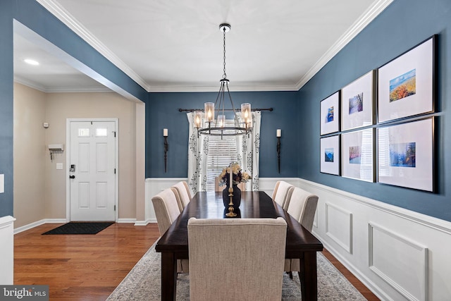 dining room with hardwood / wood-style flooring, crown molding, and an inviting chandelier