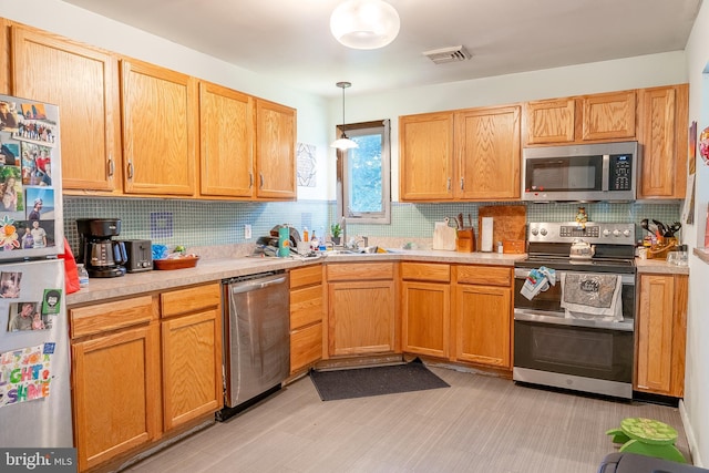 kitchen with decorative backsplash, sink, pendant lighting, and appliances with stainless steel finishes