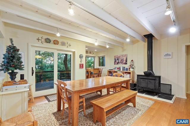 dining area with beamed ceiling, light hardwood / wood-style flooring, a wood stove, and wooden ceiling