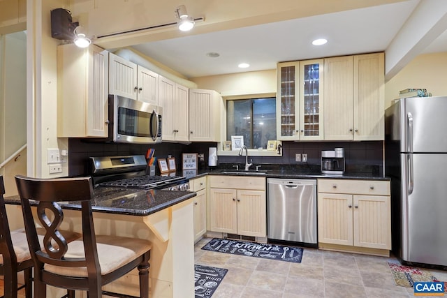 kitchen featuring dark stone counters, a kitchen breakfast bar, sink, tasteful backsplash, and stainless steel appliances