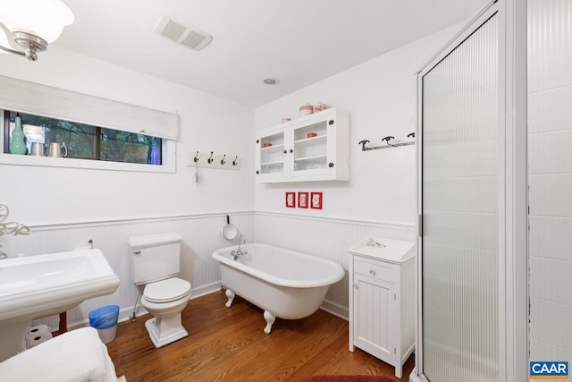 bathroom featuring a washtub, wood-type flooring, and toilet