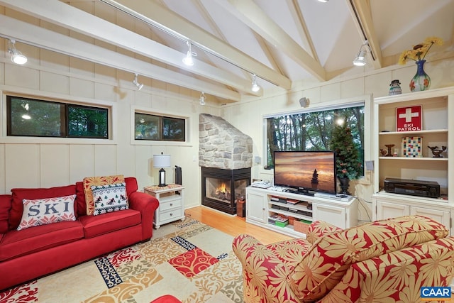 living room with vaulted ceiling with beams, light wood-type flooring, and a fireplace