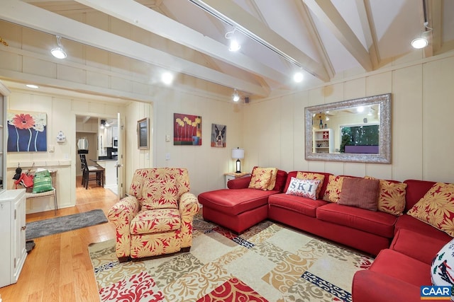 living room with vaulted ceiling with beams and light hardwood / wood-style floors