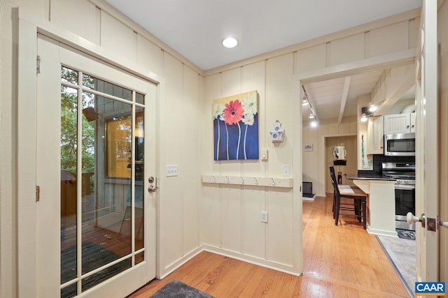 doorway with light hardwood / wood-style flooring and beamed ceiling