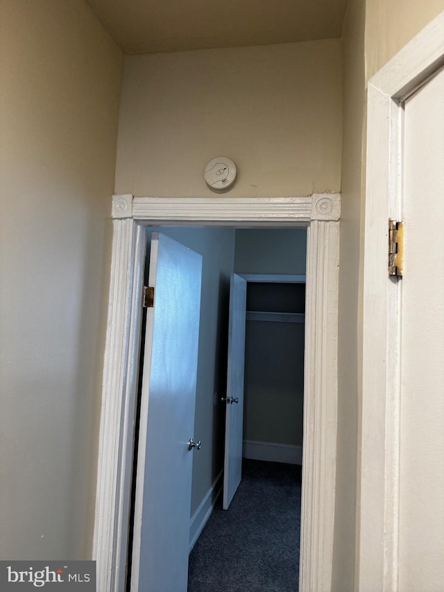 hallway with dark colored carpet