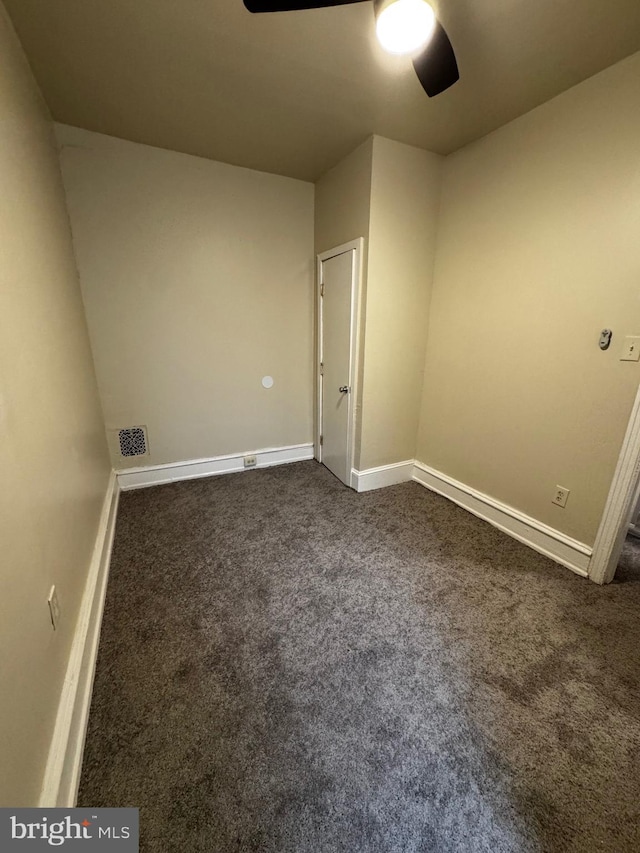 spare room with ceiling fan and dark carpet