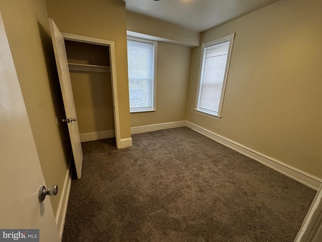 unfurnished bedroom featuring dark colored carpet and a closet