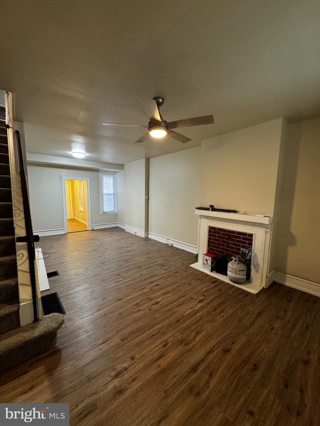 unfurnished living room with ceiling fan, a fireplace, and dark wood-type flooring