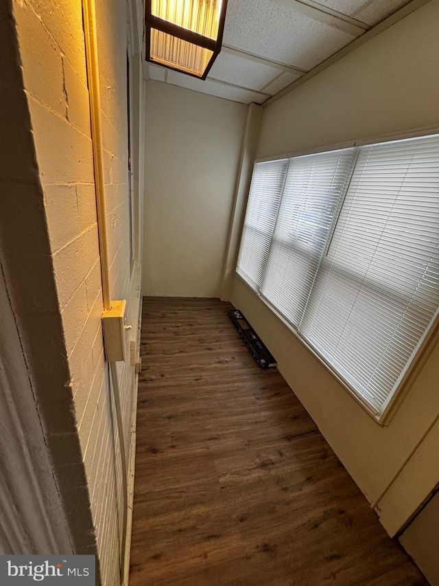 corridor with a paneled ceiling and dark hardwood / wood-style floors