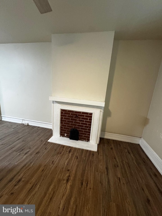 unfurnished living room with dark hardwood / wood-style floors and a brick fireplace