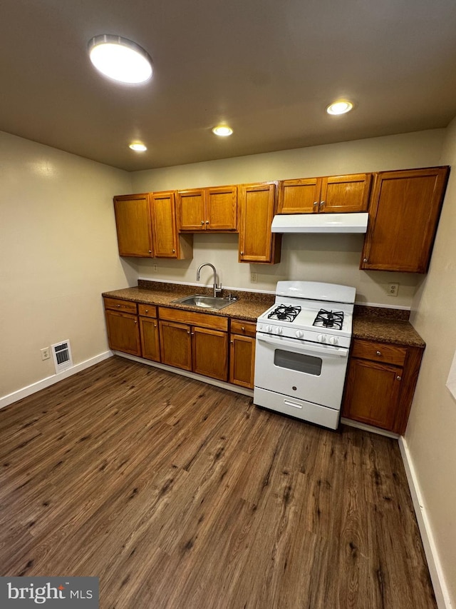 kitchen with dark hardwood / wood-style flooring, white gas stove, and sink